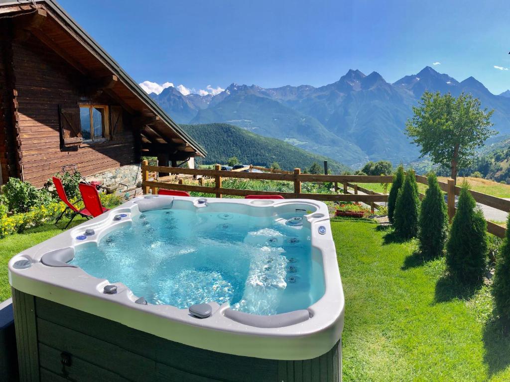 una bañera de hidromasaje en un patio con montañas al fondo en Chalet Saint-Barthélemy Hotel en Nus