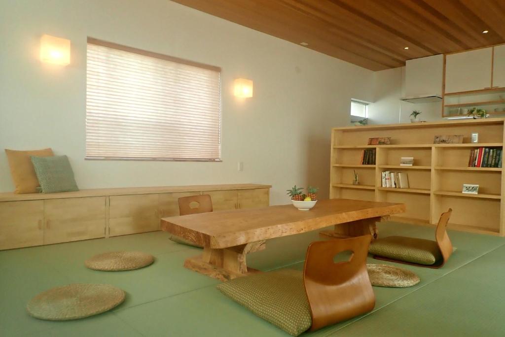 a living room with a wooden table and chairs at Guest House Ishigaki in Ishigaki Island