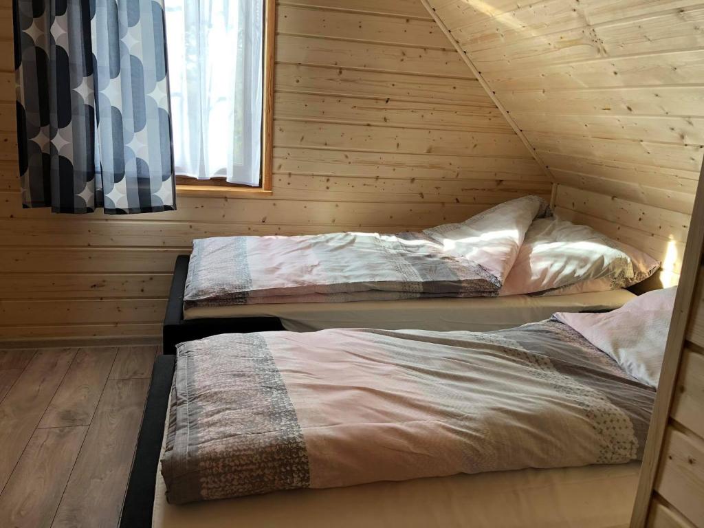 two beds in a log cabin with a window at Skrzynia 12 in Skrzynia