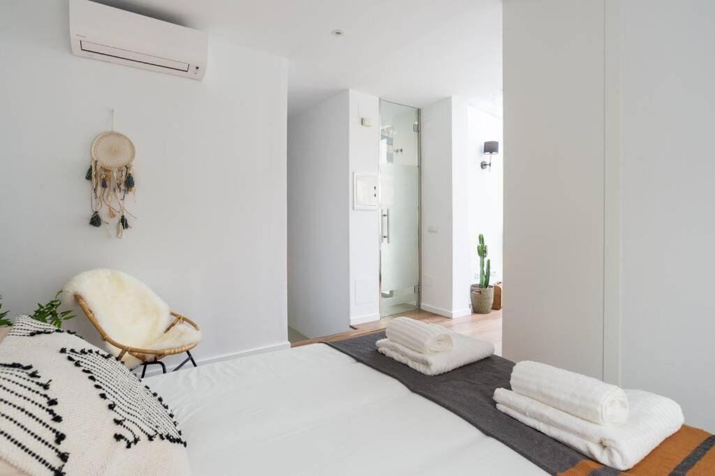 um quarto branco com uma cama e uma cadeira em TGH/ Málaga center western style em Málaga