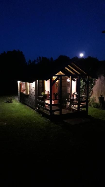 a cabin at night with a moon in the sky at Viesu māja"Ordziņas" in Pāvilosta