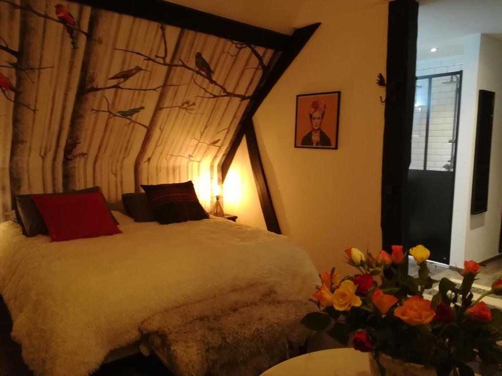 a bedroom with a bed and flowers in a room at Lait & Lit in Triqueville