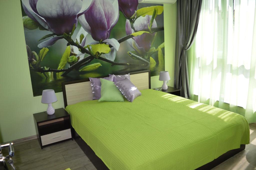Un dormitorio con una cama verde con una pintura floral en la pared en Medical University Apartments, en Plovdiv