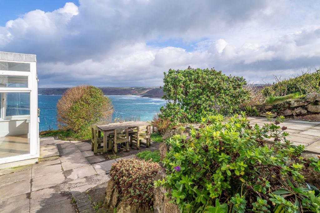 a patio with a table and a view of the ocean at Adanac in Sennen Cove