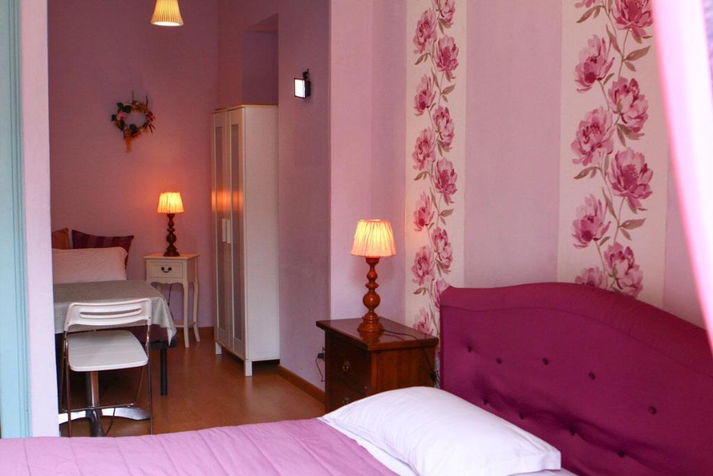 a bedroom with a purple bed and a room with a table at Duca's Guest House in Turin