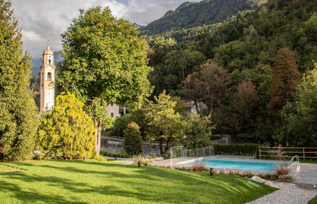 einen Garten mit einem Pool und einem Uhrturm in der Unterkunft Hotel Piuro in Prosto di Piuro