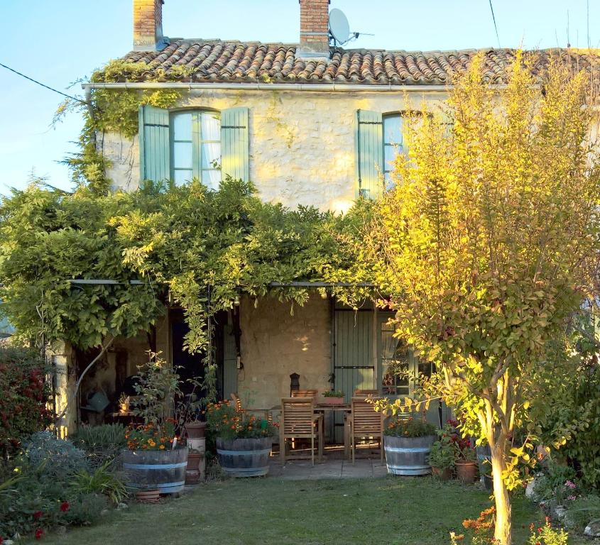 a house with a table and chairs in the yard at Les Glycines Bed & Breakfast in Eymet