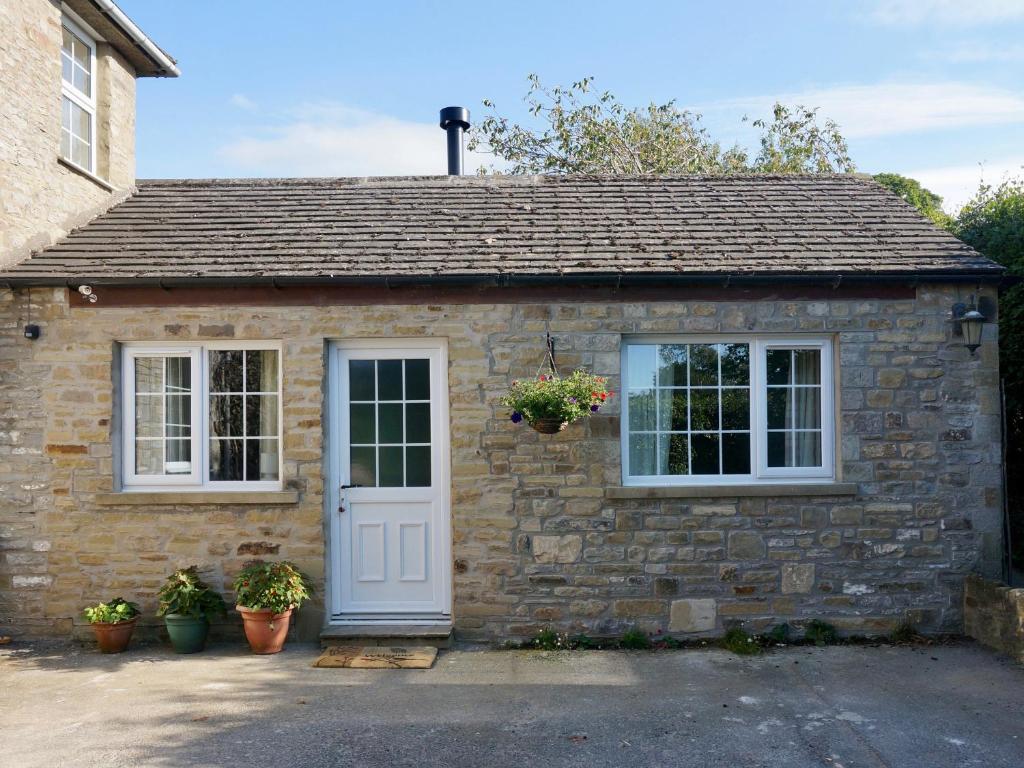 a stone cottage with a white door and windows at Fieldfare Lodge in Leyburn