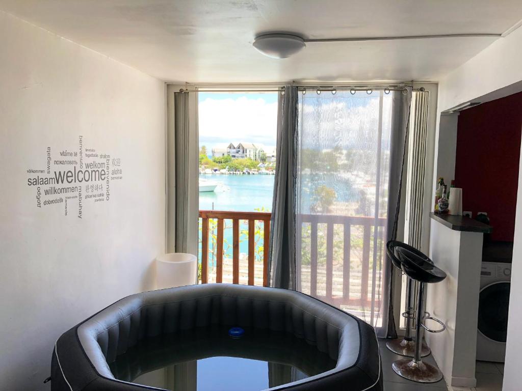 a living room with a tub in front of a window at EBT Housse, appartement, jacuzzi vue mer, 10 min aéroport et port in Baimbridge