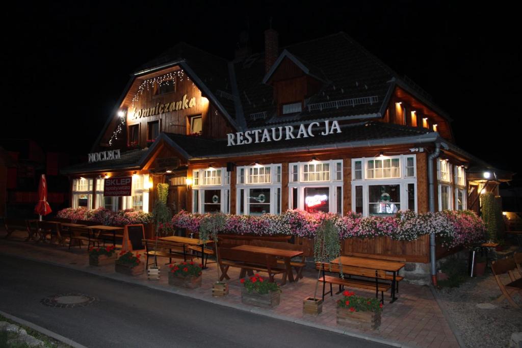 a restaurant with benches in front of it at night at Łomniczanka in Karpacz