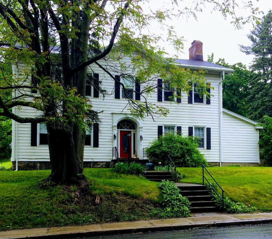 une maison blanche avec une porte rouge et un arbre dans l'établissement Gardner Farm Inn, à Troy