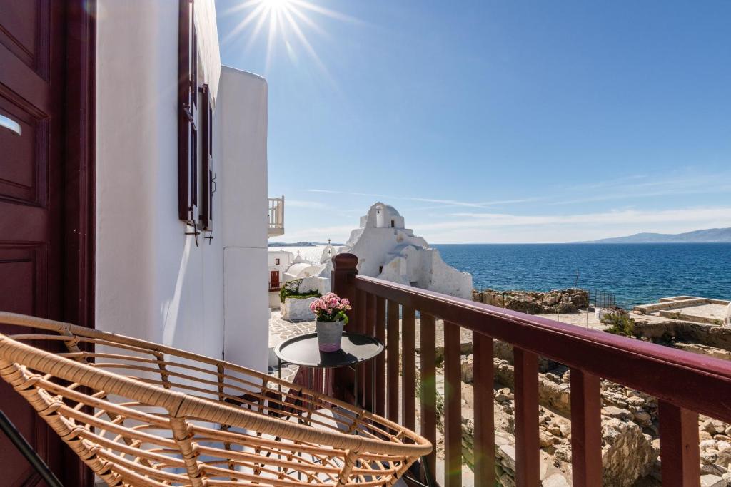 a balcony with a chair and a table and the ocean at Sunset Paraportiani Rooms in Mikonos