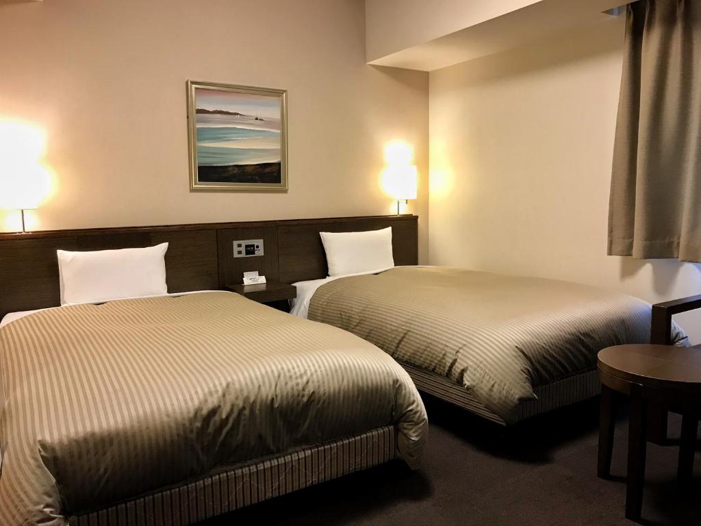 a hotel room with two beds and a table at Hotel Route-Inn Sapporo Chuo in Sapporo