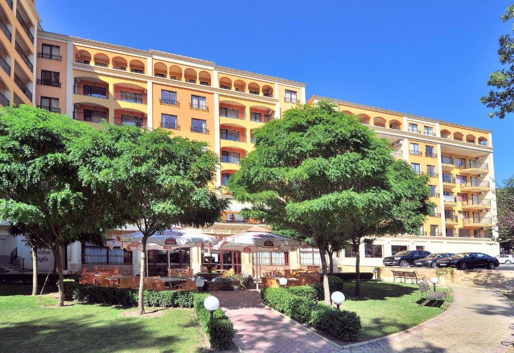 un grand bâtiment jaune avec des arbres devant lui dans l'établissement Hotel Paradise Green Park Allinclusive Light, aux Sables d'or