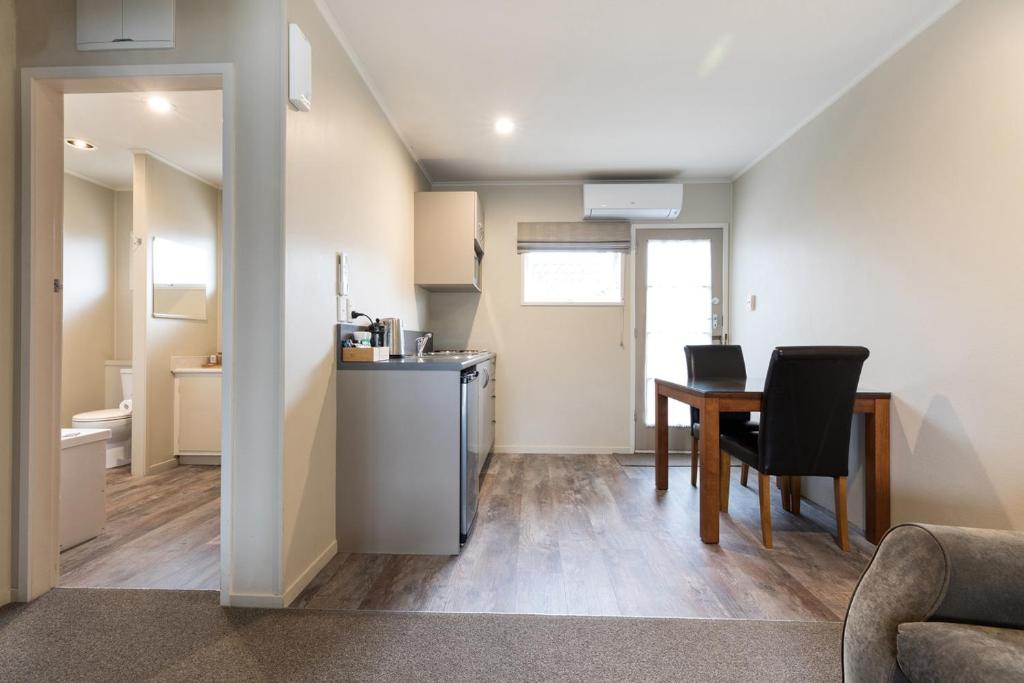 a living room with a table and a kitchen at Colonial Court Motor Inn in Tauranga