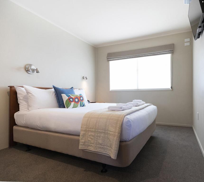 a bedroom with a large bed with a window at Colonial Court Motor Inn in Tauranga