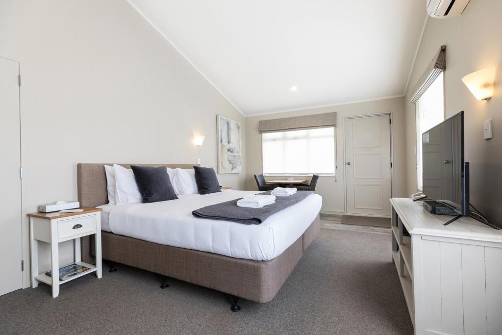 a bedroom with a large bed and a television at Colonial Court Motor Inn in Tauranga