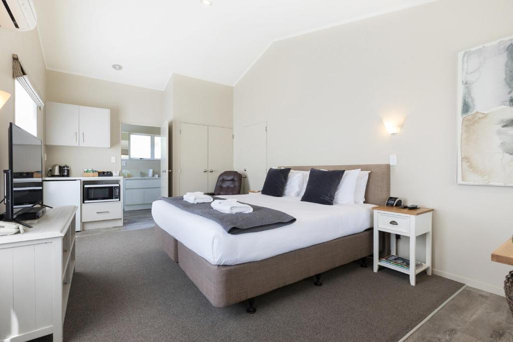 a bedroom with a large bed and a kitchen at Colonial Court Motor Inn in Tauranga
