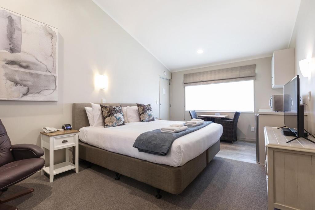 a bedroom with a bed and a living room at Colonial Court Motor Inn in Tauranga