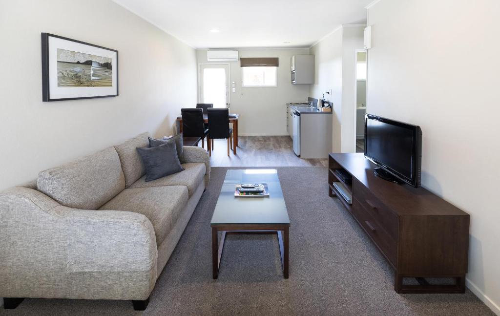 a living room with a couch and a tv at Colonial Court Motor Inn in Tauranga