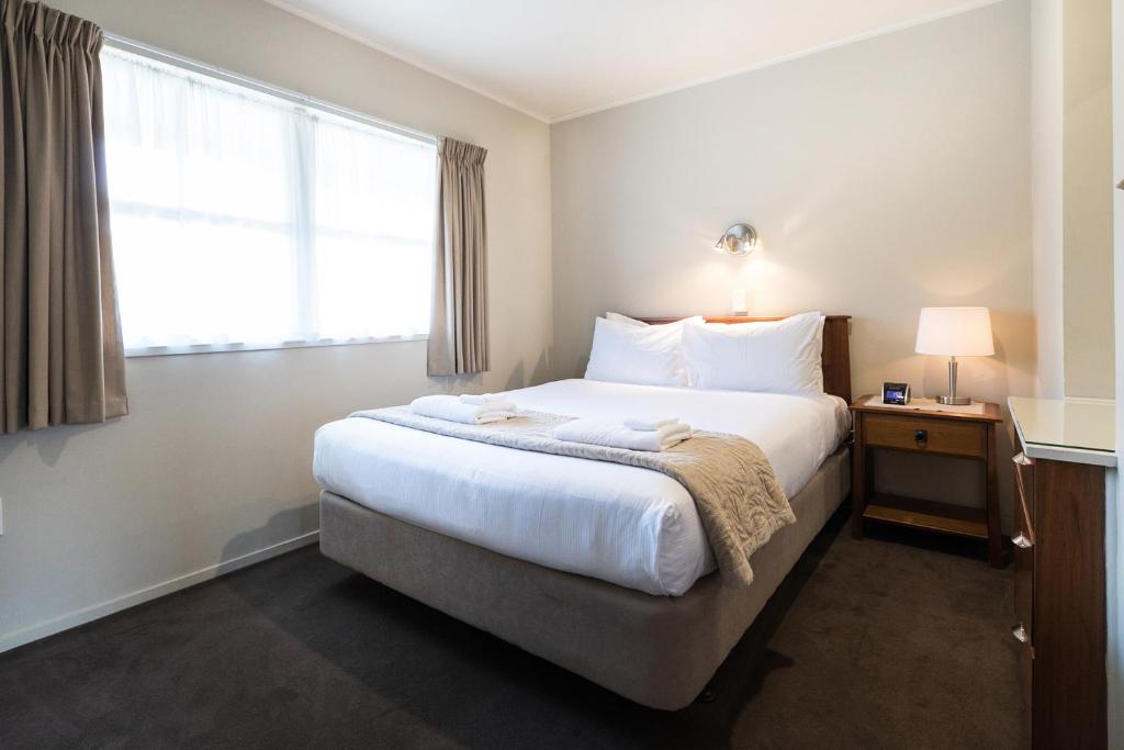 a bedroom with a large white bed with a window at Colonial Court Motor Inn in Tauranga