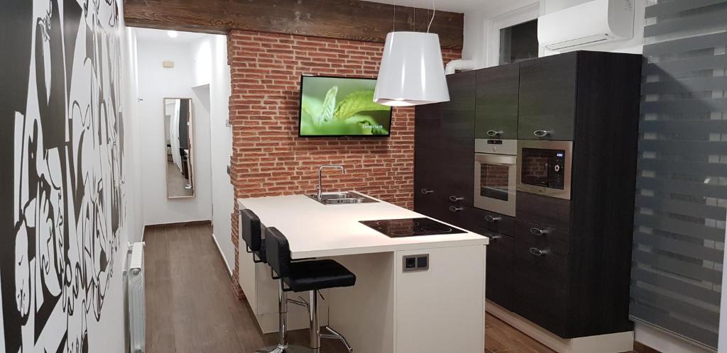a kitchen with a white counter and a brick wall at PICASSO CALLAO WiFi FREE in Madrid
