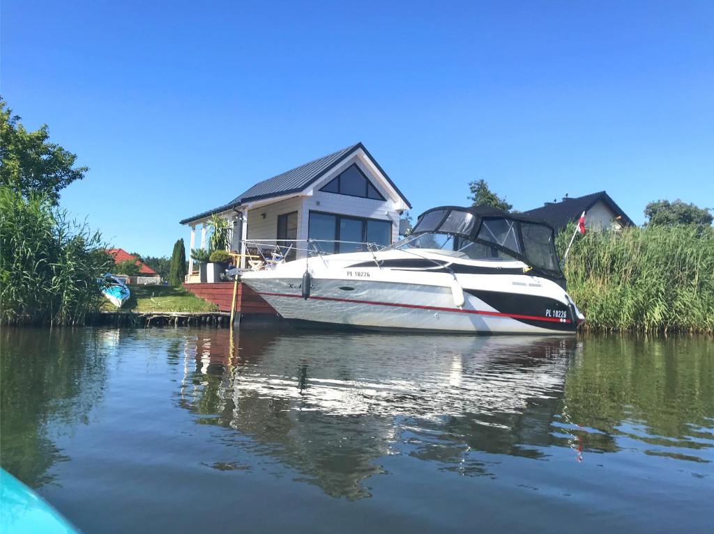 a boat parked in front of a house on the water at Baltic Waterfront Yacht House in Świnoujście