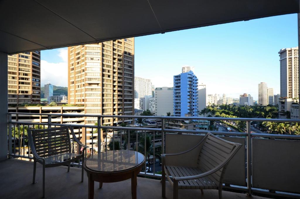 einen Balkon mit 2 Stühlen, einem Tisch und einer Stadt in der Unterkunft IH805 Waikiki 1777 Ala Moana Blvd Honolulu in Honolulu