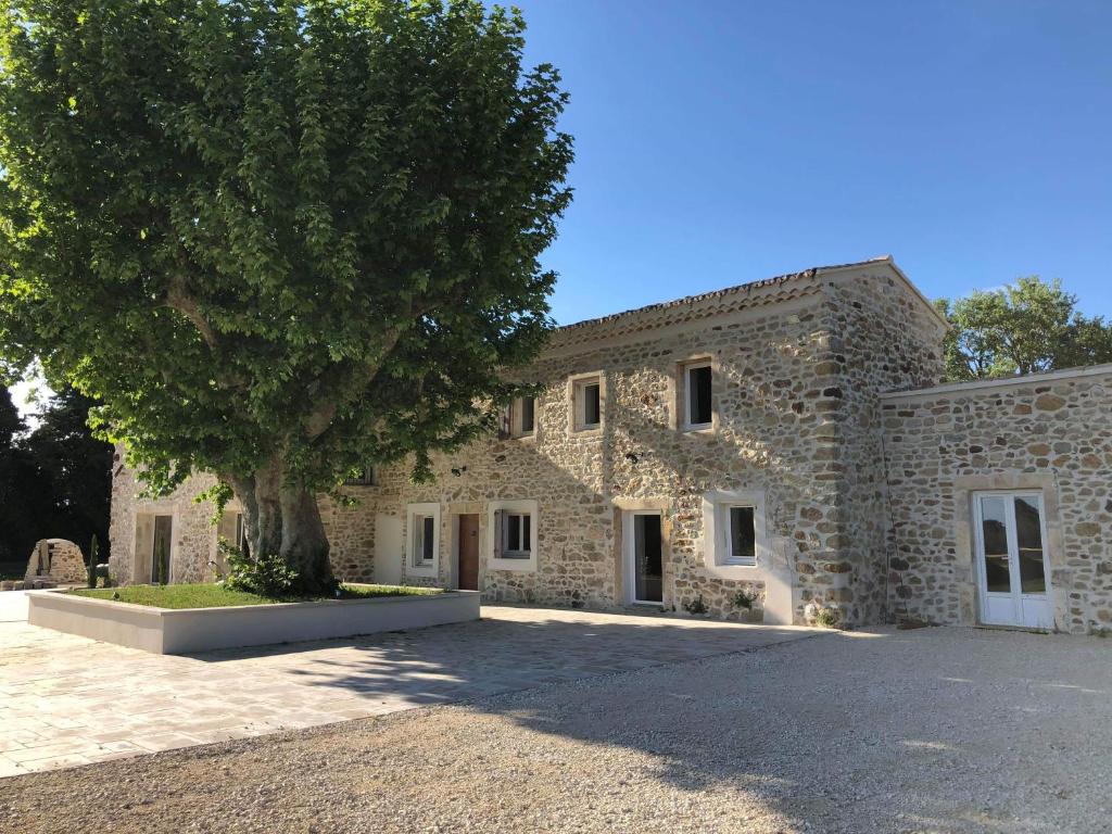 un bâtiment en pierre avec un arbre en face dans l'établissement La petite plaine, à Clansayes