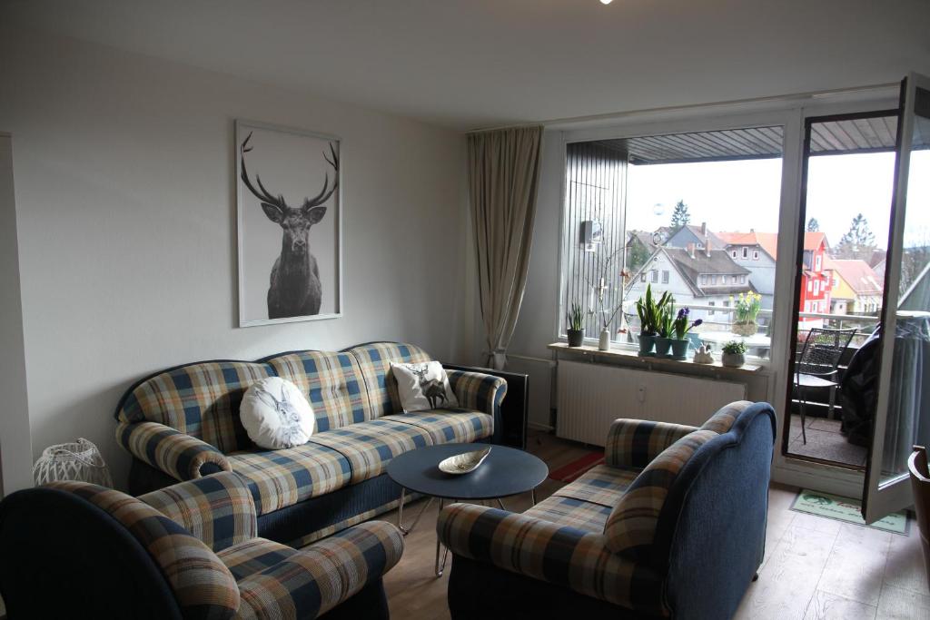 un soggiorno con divani e un cervo appeso al muro di Apartment am Kurpark a Sankt Andreasberg