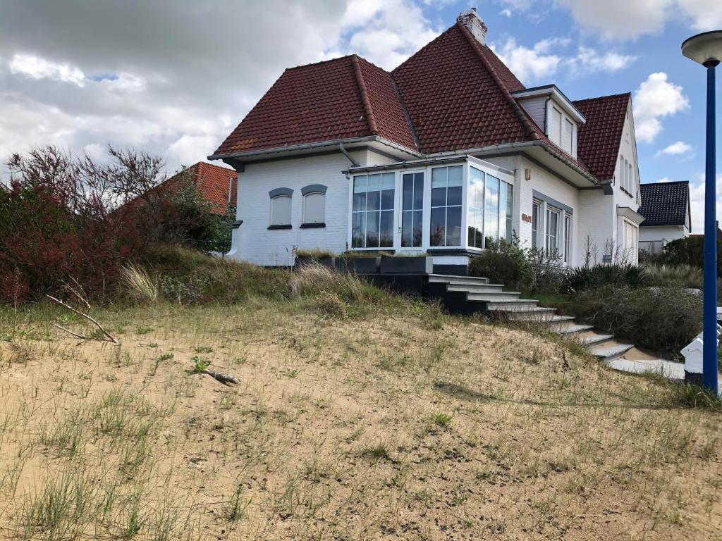 a white house with a red roof on a hill at Villa Wapi in Oostduinkerke