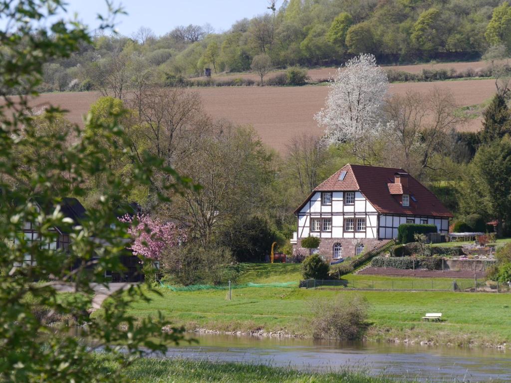 uma casa velha numa colina ao lado de um rio em Ferienwohnung Weserblick Polle em Polle