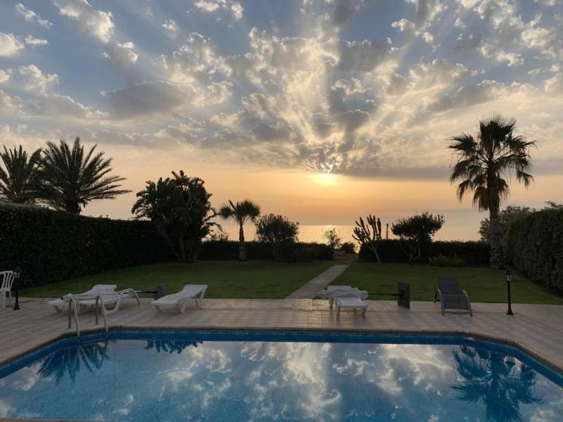 Ayia Marina的住宿－Olgas Villa，一个带椅子的游泳池,享有日落美景