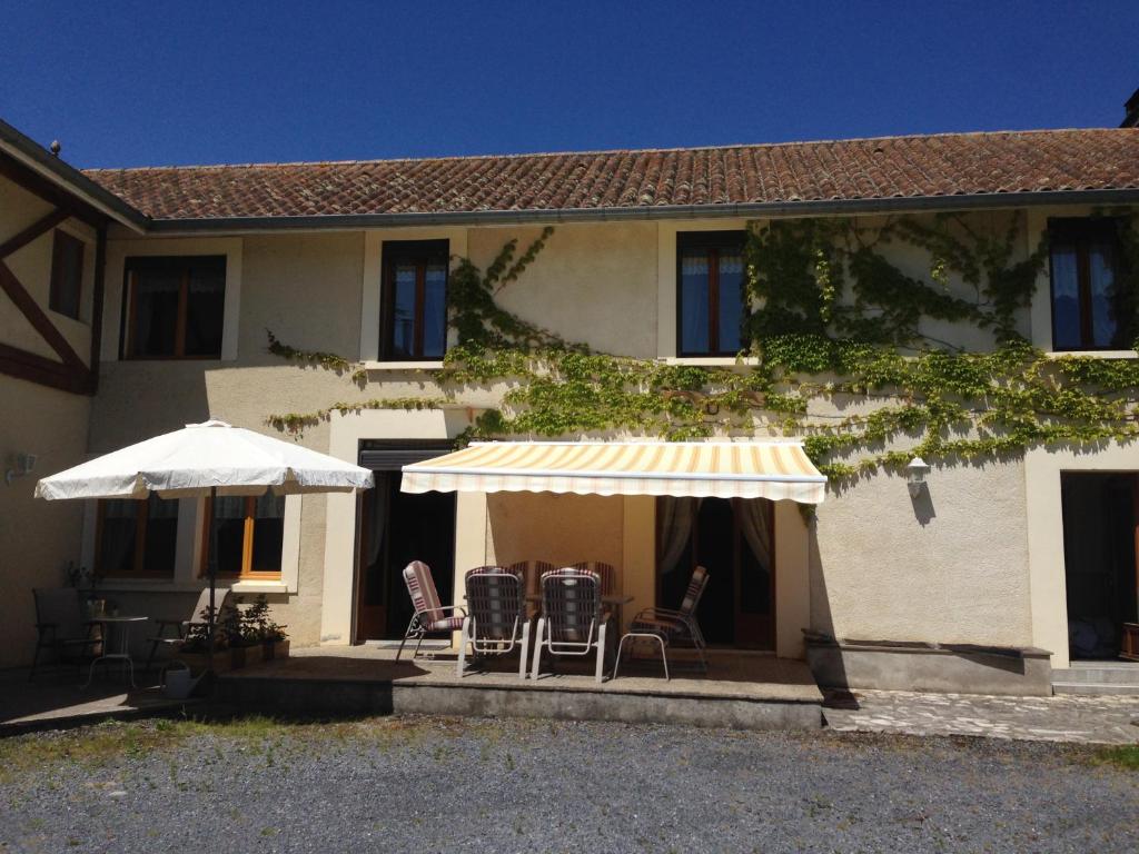 ein Haus mit einer Terrasse mit Stühlen und Sonnenschirmen in der Unterkunft Maison Cardeillac in Haget