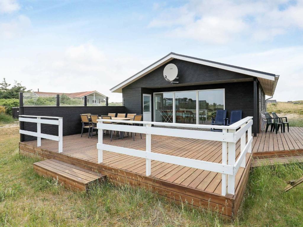 a house with a deck with a table and chairs at 8 person holiday home in Ringk bing in Ringkøbing