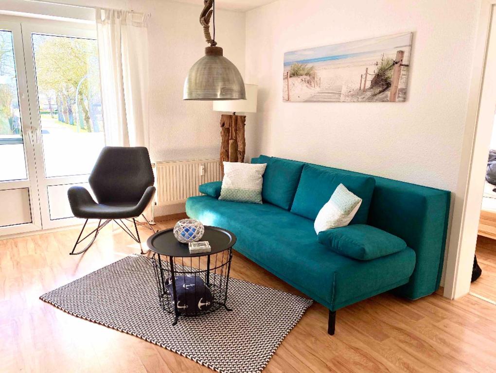 ein Wohnzimmer mit einer grünen Couch und einem Stuhl in der Unterkunft Fehmarn Oase in Petersdorf auf Fehmarn