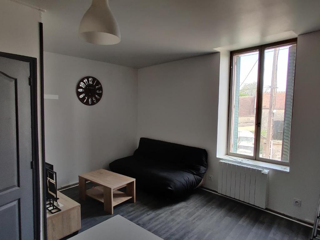 - un salon avec un canapé en cuir noir et un réveil dans l'établissement Calme 2 Pièces en Duplex, à Aufferville