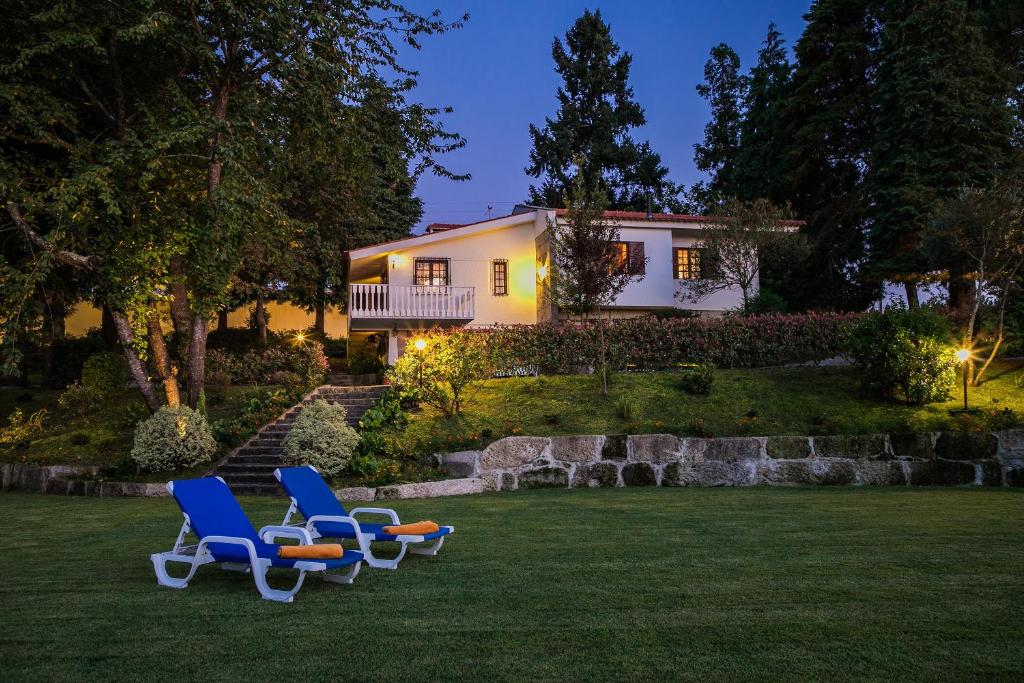 a group of chairs sitting on a lawn in front of a house at Torrinheira ~ Family Pool Villa and Woods in Travanca