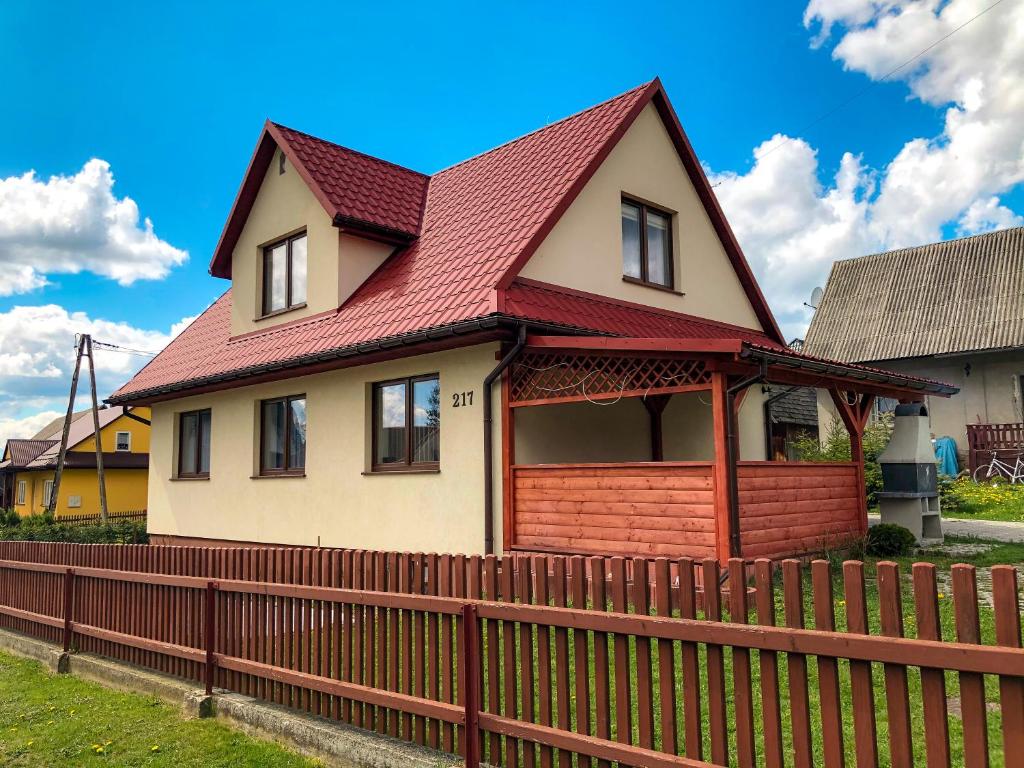 uma casa com um telhado vermelho e uma cerca em Dom u Kasi em Podwilk