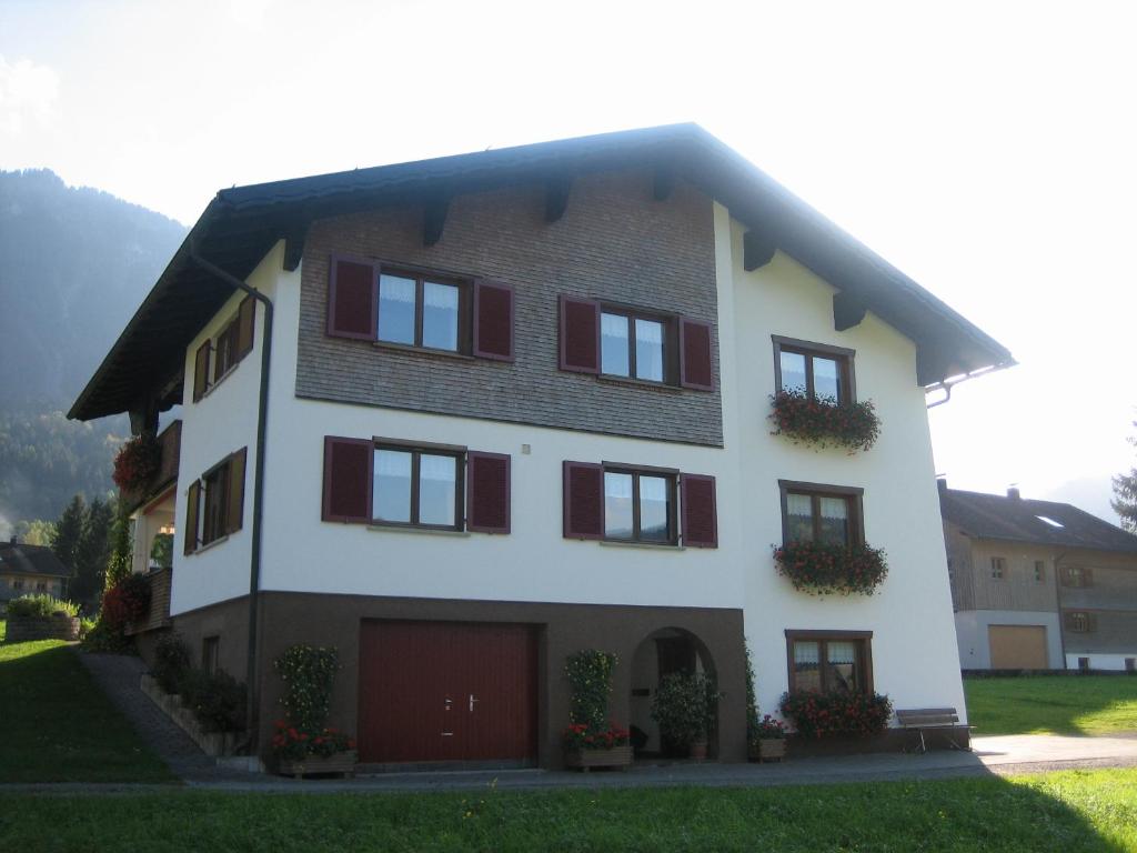 ein großes weißes Haus mit roten Rollläden in der Unterkunft Haus Margreth in Mellau