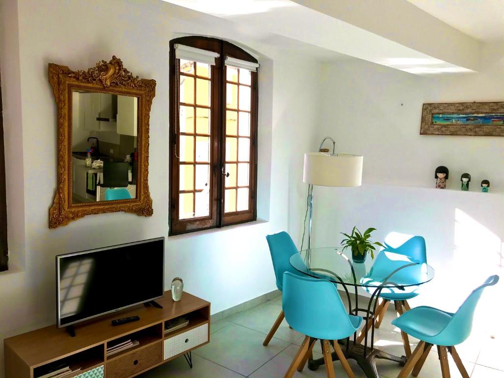 ein Wohnzimmer mit einem TV, einem Glastisch und Stühlen in der Unterkunft La Maison du Courtil, Pistache-Chocolat in Moustiers-Sainte-Marie