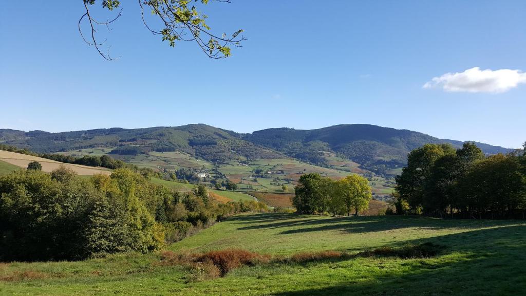 a green field with trees and mountains in the background at La Bégude D'Amalthée in Vernay