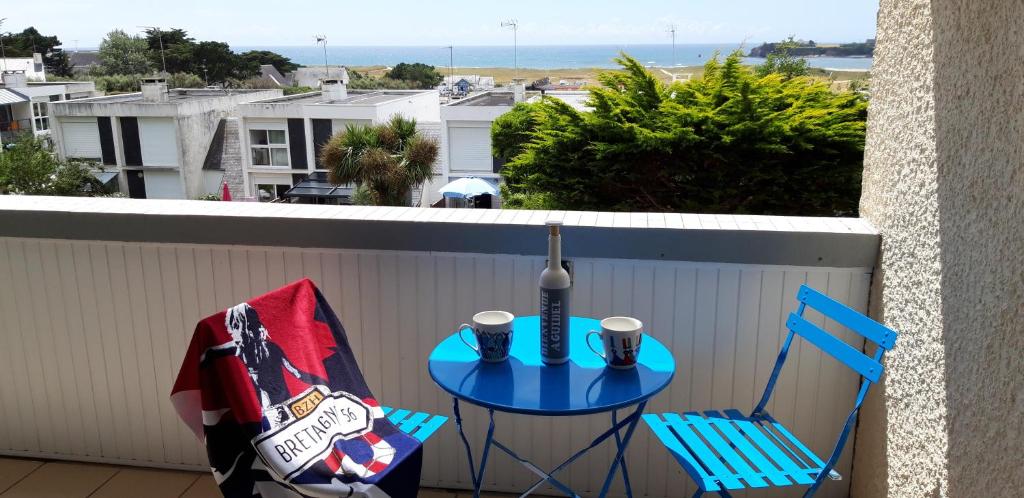 d'une table bleue et de deux chaises sur un balcon. dans l'établissement Appartement ,le Trimaran, avec vue sur l'océan, à Guidel