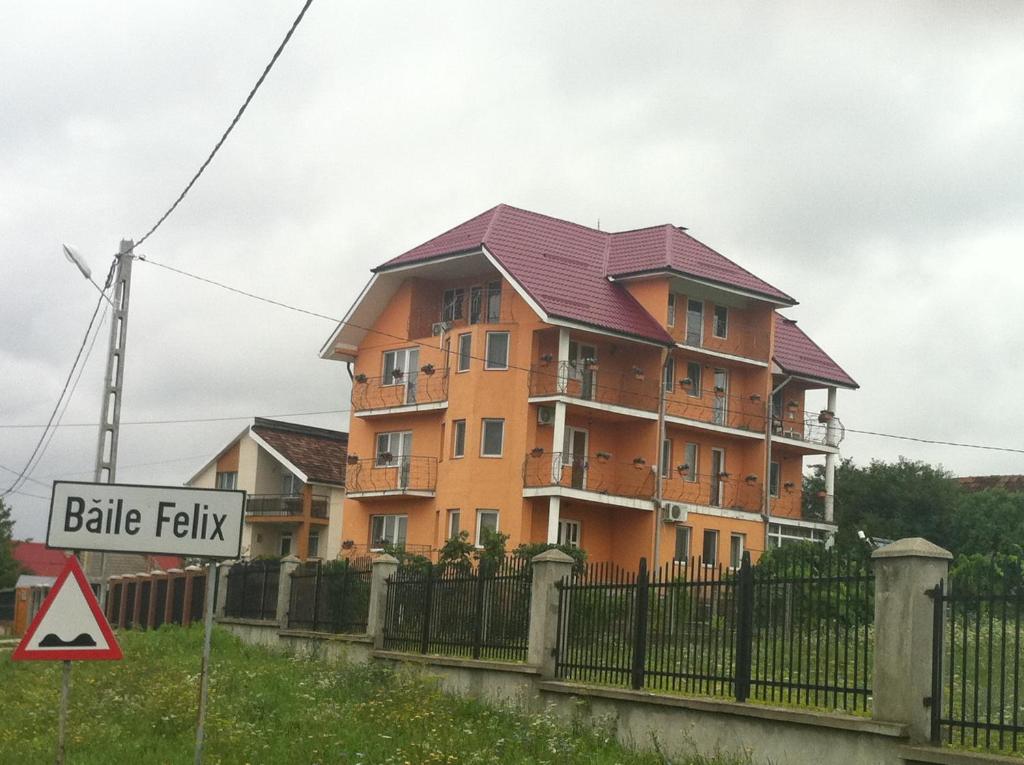 a large orange building behind a fence with a sign at pensiunea vanesa in Baile Felix