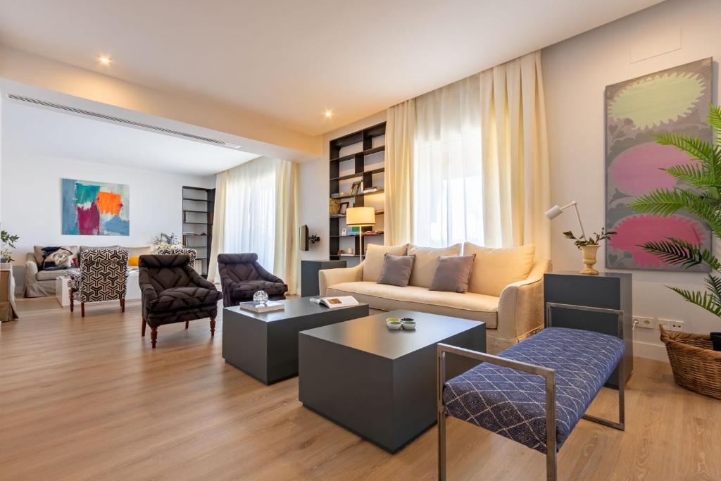 - un salon avec un canapé, des tables et des chaises dans l'établissement Plaza de España Deluxe Suites, à Séville