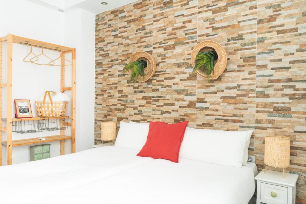 マラガにあるピクニック ドリーム ブティック ホステルの白いベッドとレンガの壁が備わるベッドルーム1室が備わります。