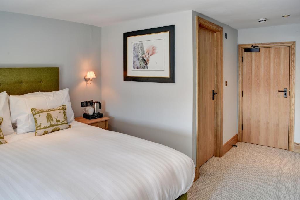 a bedroom with a white bed and a wooden door at Barn Owl Inn in Newton Abbot