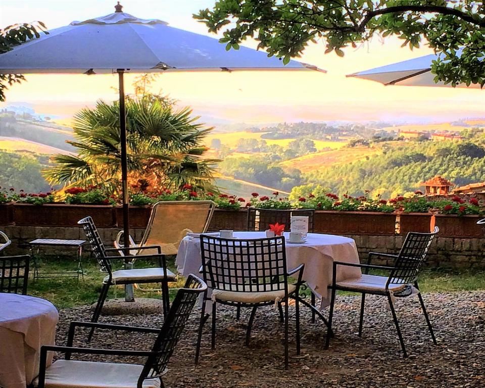 a table with chairs and an umbrella with a view at Hotel Santa Caterina in Siena