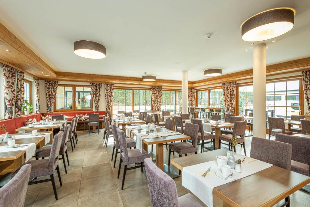 un ristorante con tavoli, sedie e finestre di Hotel Garni Melanie a Wals-Siezenheim