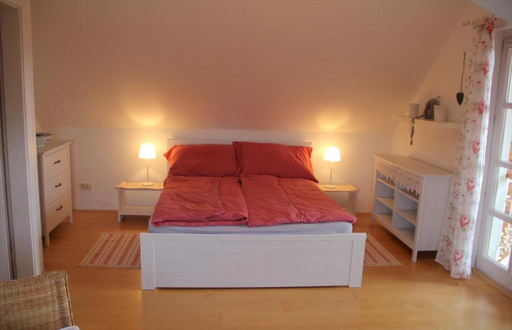 a bedroom with a bed with red sheets and two lamps at ALPHA in Badacsonytördemic